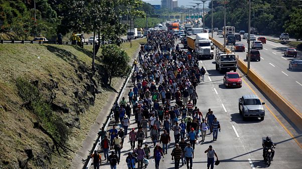 People walk in a caravan of migrants en route to the US in El Salvador. People walk in a caravan of migrants en route to the US in El Salvador.