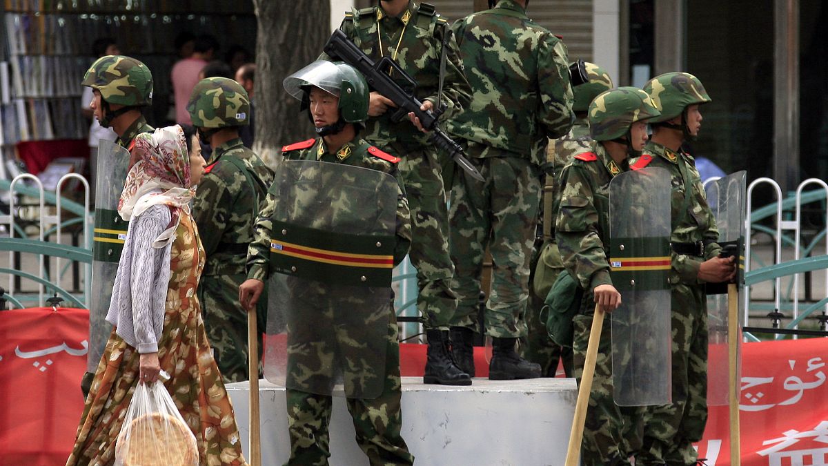 Doğu Türkistan'ın Urumçi kentinde, Çinli askerlerin önünden geçen Uygur kız