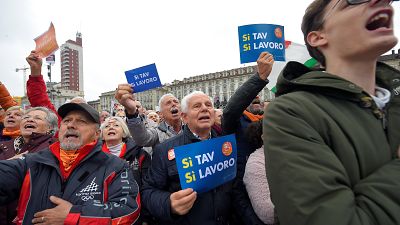 A man holds a placard reading "Yes Tav, Yes job" 