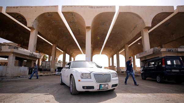 Ein jordanisches weißes Auto steht vorm Grenzübergang Ein jordanisches weißes Auto steht vorm Grenzübergang
