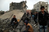 Palästinenser sitzen auf den Überresten eines zerstörten Gebäudes