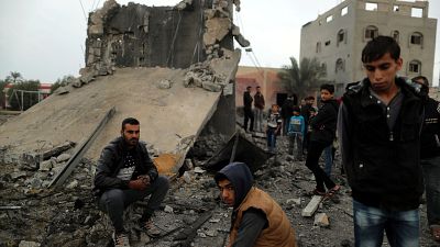 Palästinenser sitzen auf den Überresten eines zerstörten Gebäudes