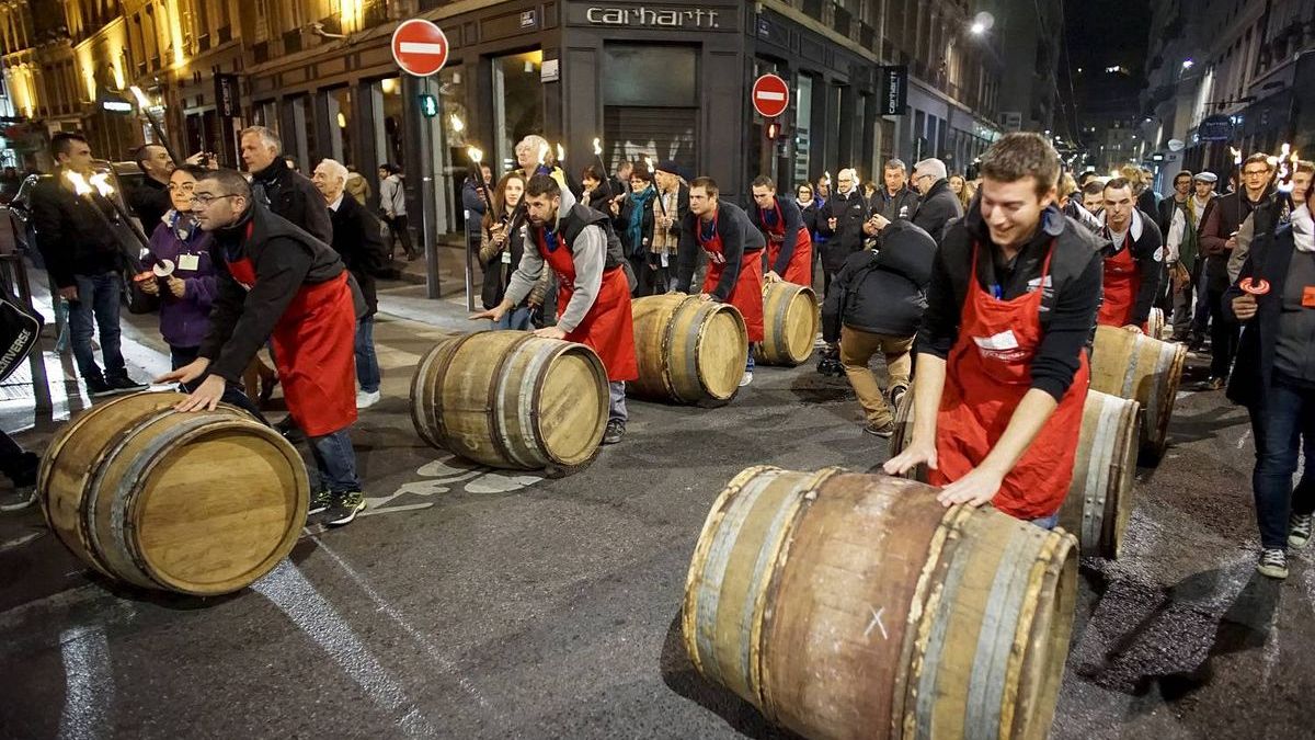 Men roll barrels of Beaujolais Nouveau wine 