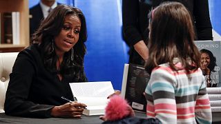 Former first lady Michelle Obama signs a copy of her memoir "Becoming".