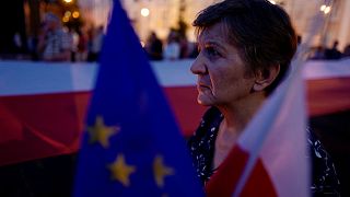 Woman holds flags during an anti-government protest in Warsaw