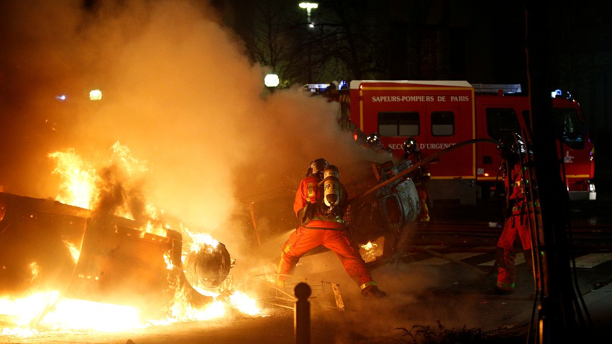 Firemen extinguish burning cars set alight by protesters
