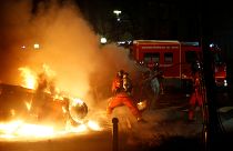 Firemen extinguish burning cars set alight by protesters