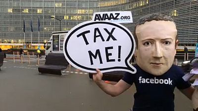 شاهد: ممثل يرتدي قناع مارك زوكربيرغ للمطالبة بفرض ضريبة على عمالقة الرقميات