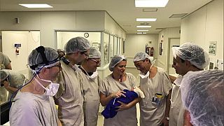 Medical team hold the first baby born via uterus transplant