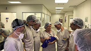 Medical team hold the first baby born via uterus transplant 