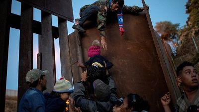 Migrants jump a border fence to cross illegally from Mexico to the U.S.