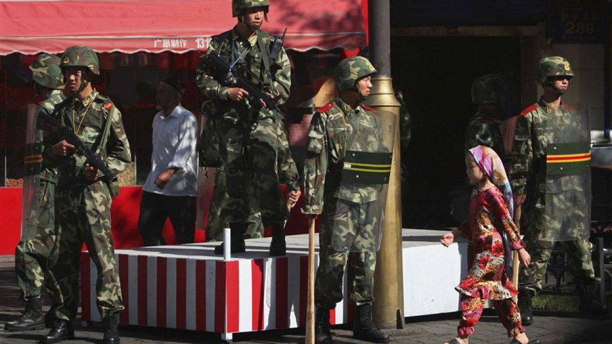 Doğu Türkistan'ın Urumçi kentinde, Çinli askerlerin önünden geçen Uygur kız
