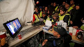 Protesters watch French President Emmanuel Macron on a TV screen on Dec 10