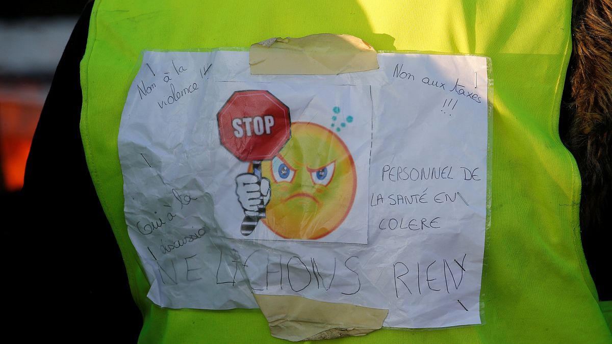 A protester wears a yellow vest bearing the slogan "don't give up."