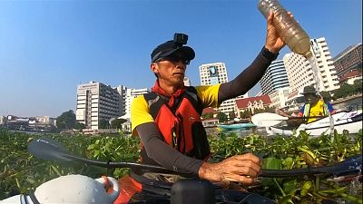 أحد الناشطين يجمع النفايات التي رميت في نهر شاو برايا التايلاندي