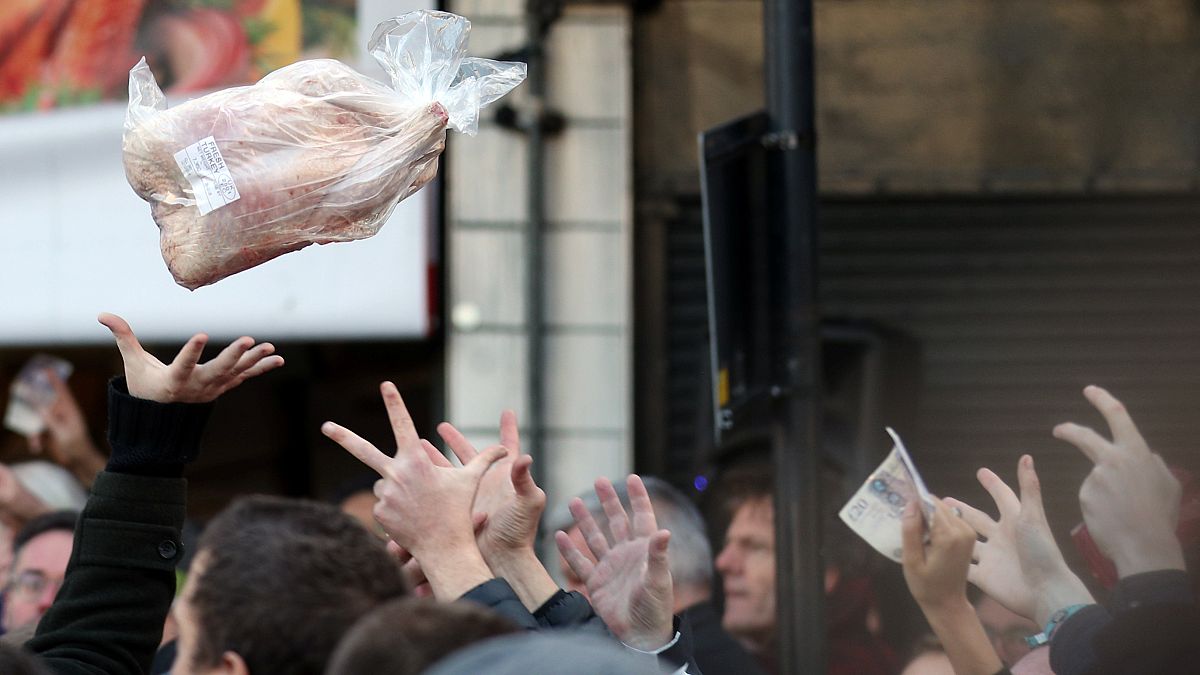 Shoppers bid for cuts of meat during a Christmas Eve auction in London