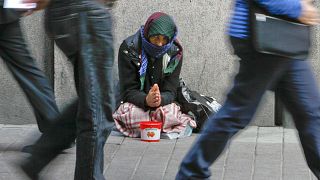 A woman begs for money on a street in downtown Helsinki.