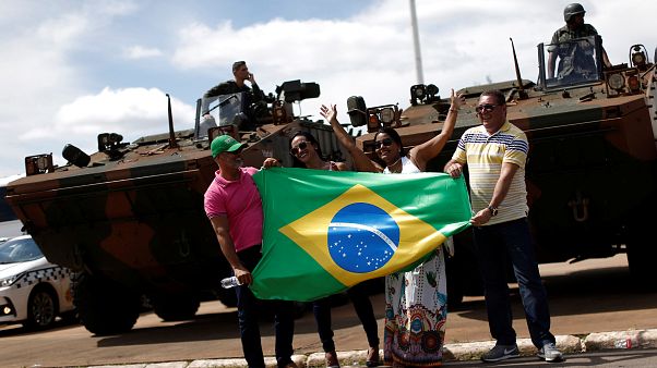 Menschen halten die brasilianische Flagge vor Militärfahrzeugen Menschen halten die brasilianische Flagge vor Militärfahrzeugen