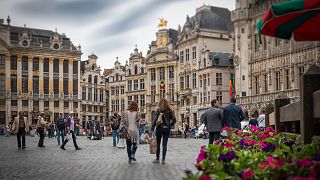 People walk across the Grand Place Square in Brussels, Belgium.