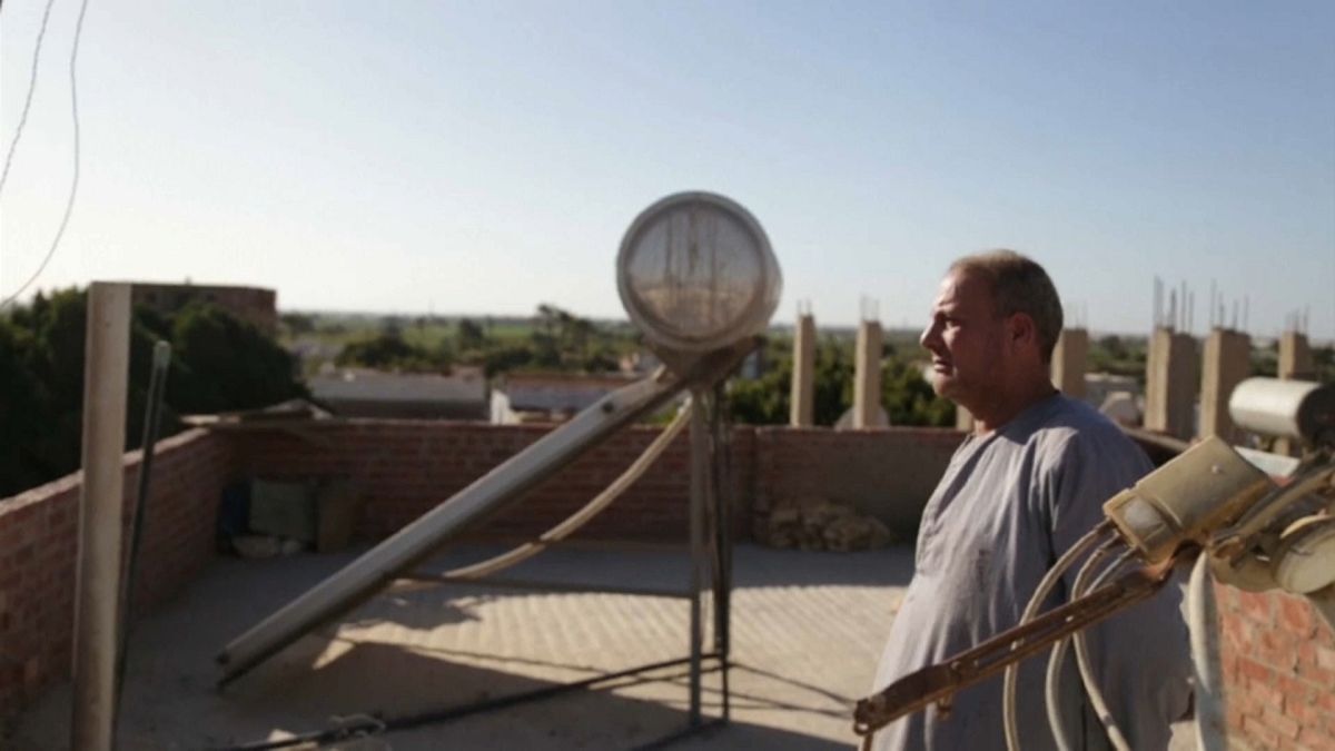 Ein Mann steht auf dem Dach neben einem Sonnenkollektor