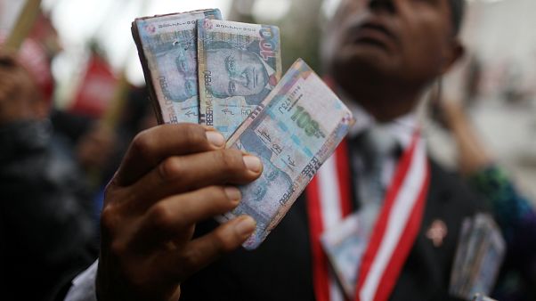Un manifestant tenant des faux billets, à Lima, Pérou, le 3 janvier 2019 Un manifestant tenant des faux billets, à Lima, Pérou, le 3 janvier 2019