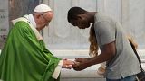 Pope Francis is greeted by a migrant as he celebrates a mass for migrants