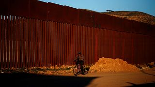 A man cycles along the US border in Tijuana, Mexico.