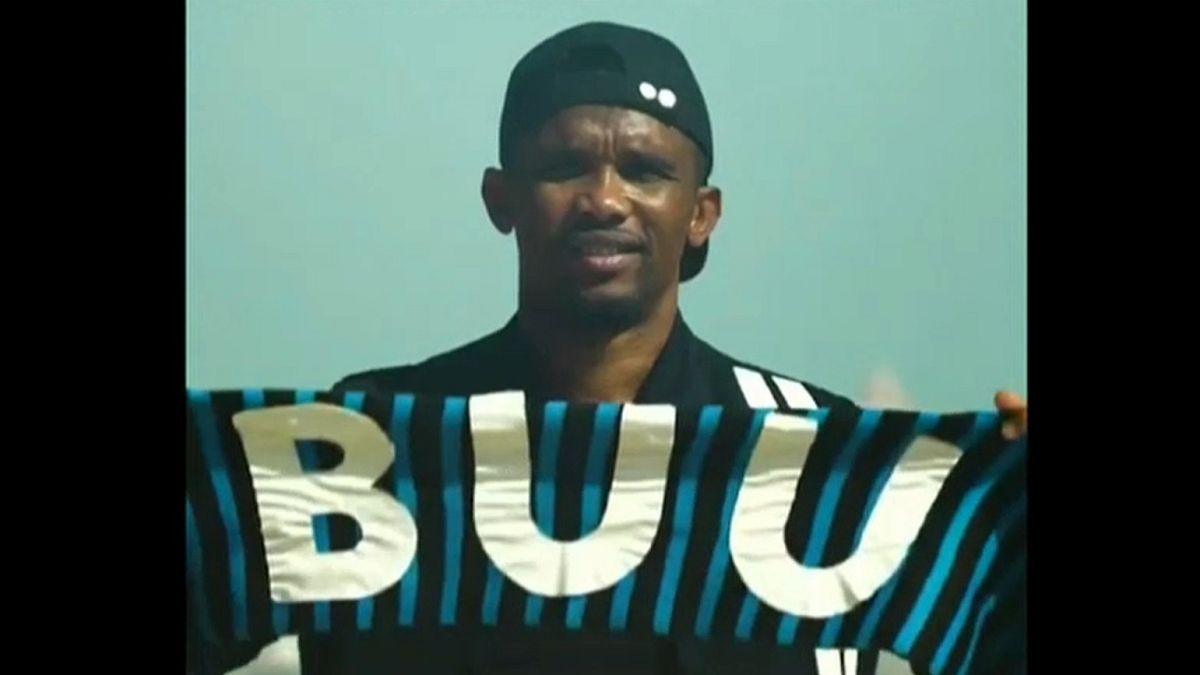 Samuel Eto'o hält einen schwarz-blauen Schal mit der Aufschrift "BUU"