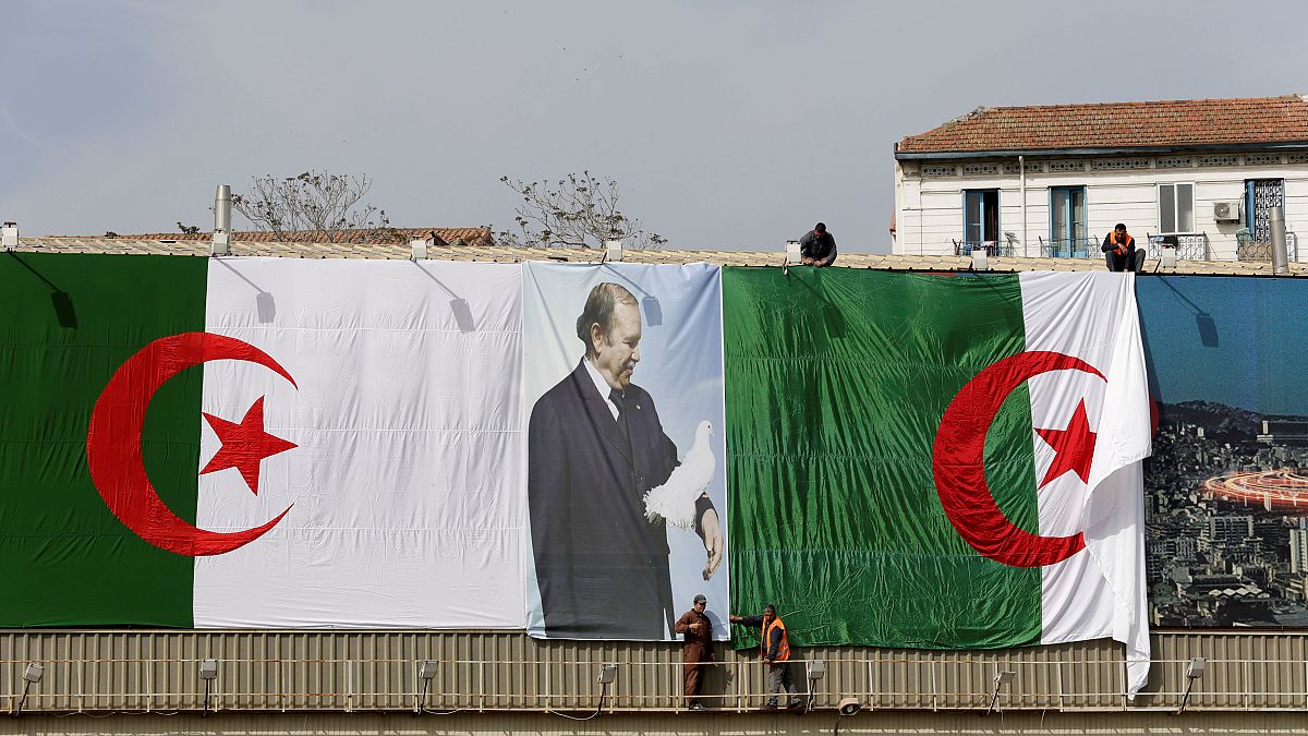 عمال جزائريون يعلقون علم بلادهم قبيل الانتخابات النيابية في 2017