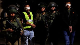 İsrail askerleri Batı Şeria'da bir Filistinli kameramanı göz altına alırken