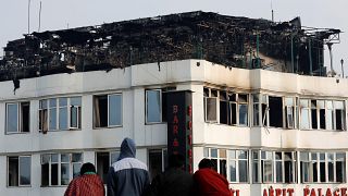 أشخاص على سطح مبنى ينظرون إلى الفندق حيث اندلعت النيران