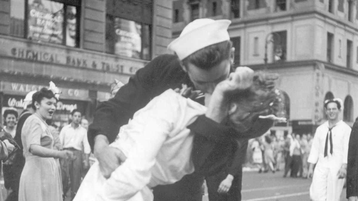 A jubilant American sailor clutching a white-unifo