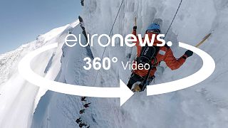 A man is pick climbing an ice hill