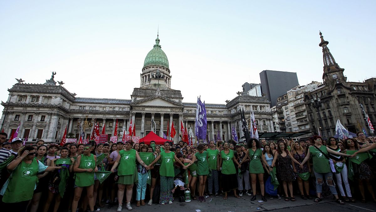 Activists hold hands outside the Argentine National Congress