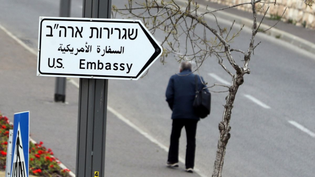 رجل يسير بجوار لافته تشير إلى اتجاه السفارة الإسرائيلية في القدس