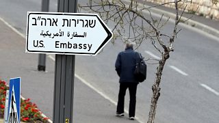 رجل يسير بجوار لافته تشير إلى اتجاه السفارة الإسرائيلية في القدس