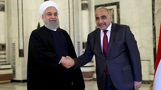 رئيس الوزراء العراقي عادل عبد المهدي (إلى اليمين) يصافح الرئيس الإيراني حسن