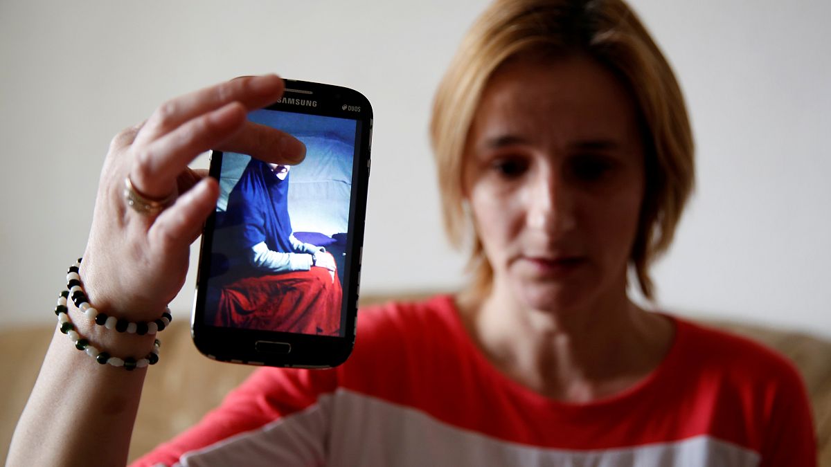 سيدة بوسنية تحمل هاتف محمول عليه صورة أختها في سوريا