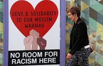 امرأة تمر بجانب منشور يدعم مسلمي نيوزيلندا بعد مذبحة المسجدين
