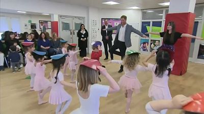 Dad-to-be Prince Harry observes a ballet class and makes a baby smile while visiting a YMCA