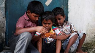 Children play a game on a mobile phone at slum area in New Delhi