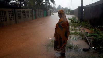 Eine Frau steht in Pemba vor einer überschwemmten Straße