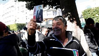 رجل يحمل صورة الرئيس السابق زين العابدين بن علي خلال الاحتفال بذكرى الثورة
