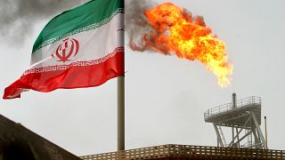 العلم الإيراني وفي الخلف مدخنة في منشأة نفطية
