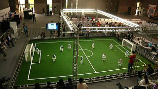 Falling and scoring, robots compete on football pitch