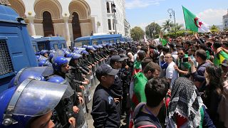 أفراد من الشرطة يقفون حراسة فيما يحتج طلاب ضد الحكومة في الجزائر