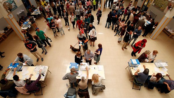 People cast their votes at a ballot station People cast their votes at a ballot station
