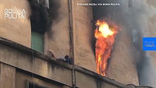 Man clings to outer shelf as flames rage from his Rome room