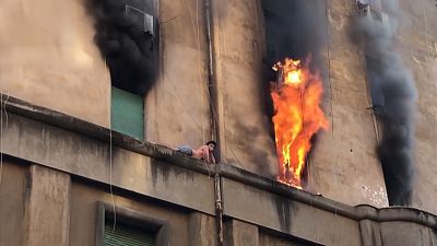 Man clings onto ledge as building burns in Rome