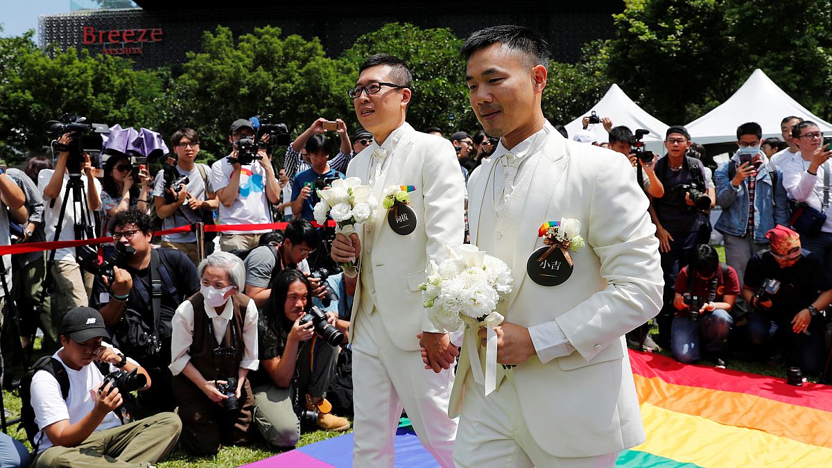 Gay newlyweds walk on a giant rainbow flag in Taipei on May 24, 2019.